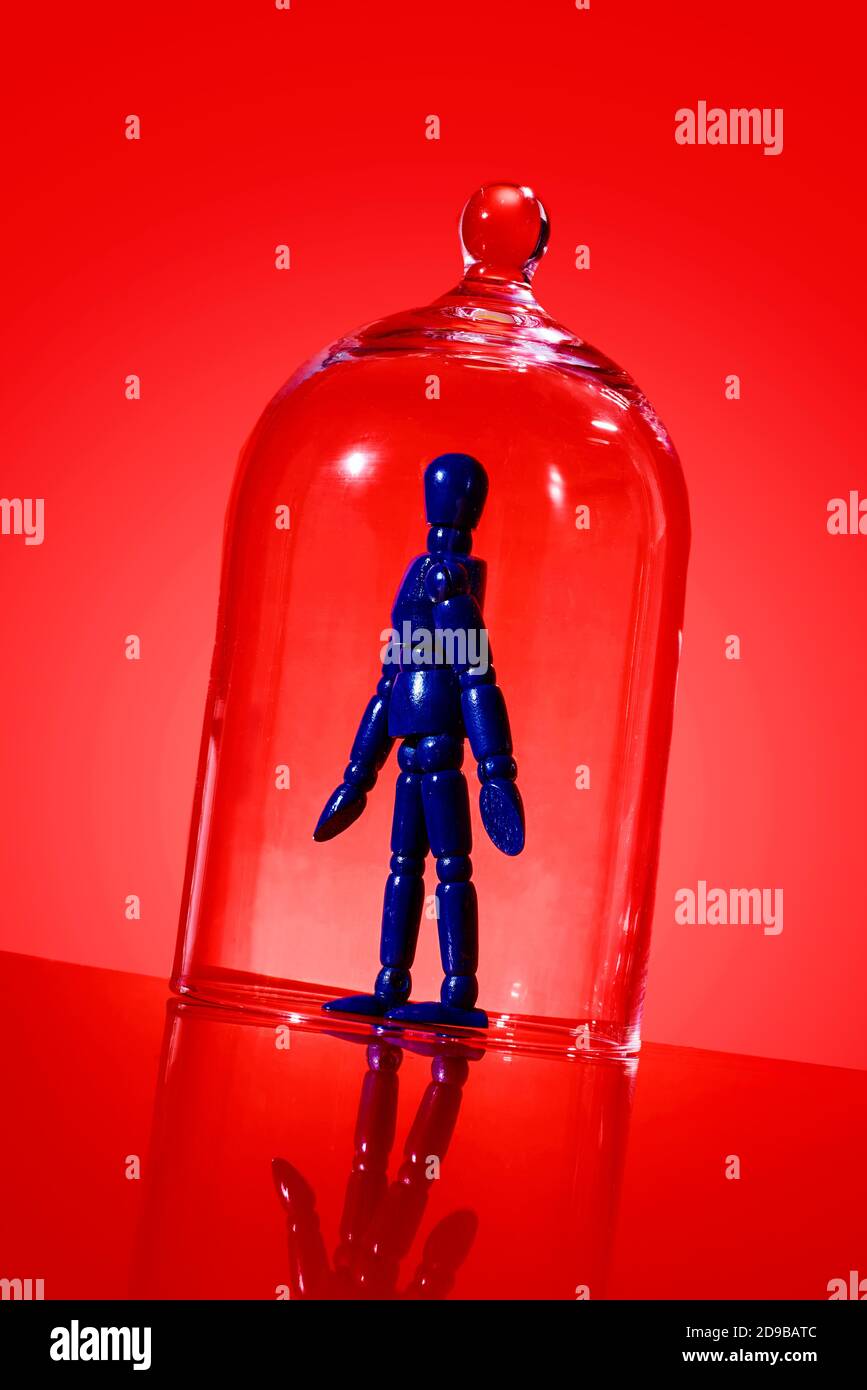 une poupée bleue articulée dans un verre cloche sur un arrière-plan rouge Banque D'Images