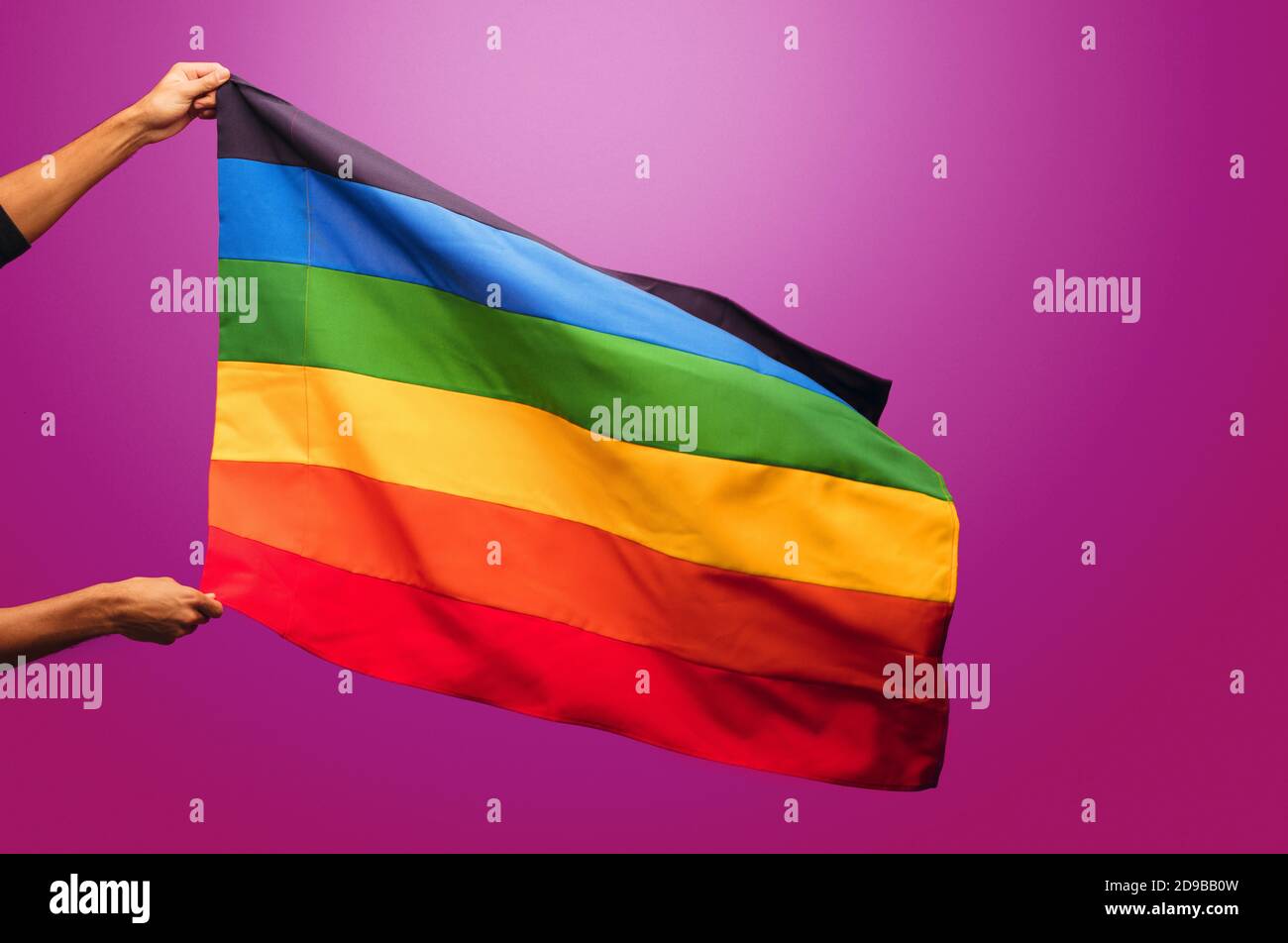 Prise de vue courte des mains portant le drapeau de fierté gay sur fond violet. Drapeau de fierté lgbt coloré par arc-en-ciel. Banque D'Images