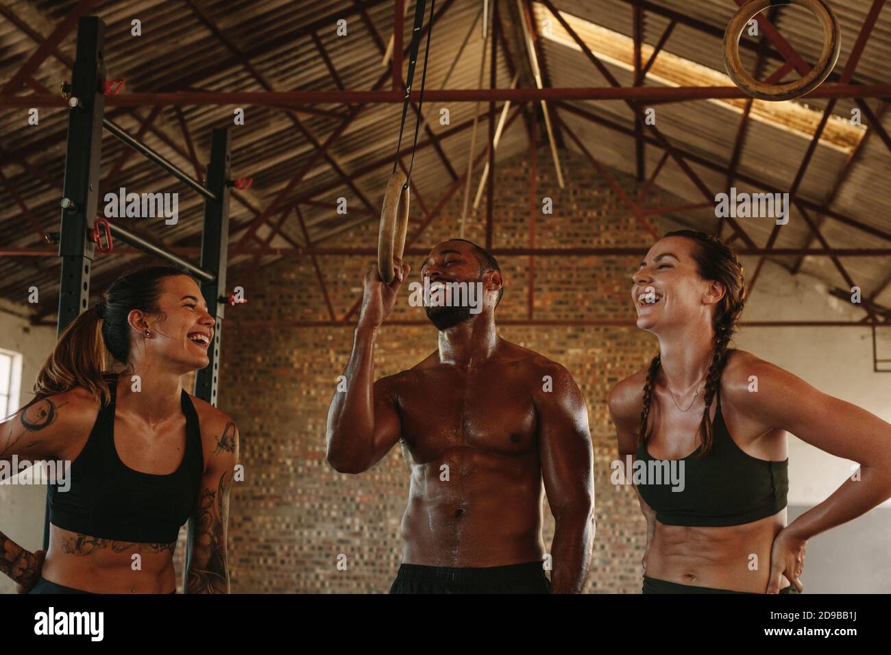 Groupe de personnes prenant le repos après l'entraînement physique. Des jeunes heureux se détendent et parlent au studio de fitness à l'ombre d'une ancienne usine. Banque D'Images