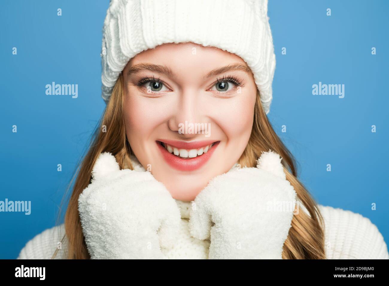 portrait de femme souriante belle en hiver blanc tenue isolée sur bleu Banque D'Images