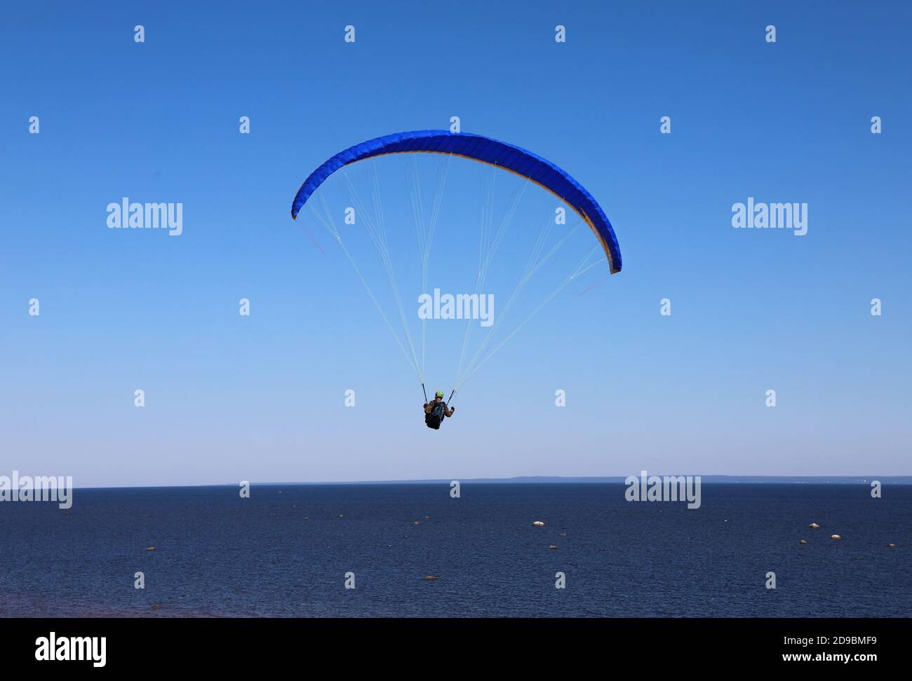 Parapente homme dans les airs. Ciel bleu et mer en arrière-plan Banque D'Images