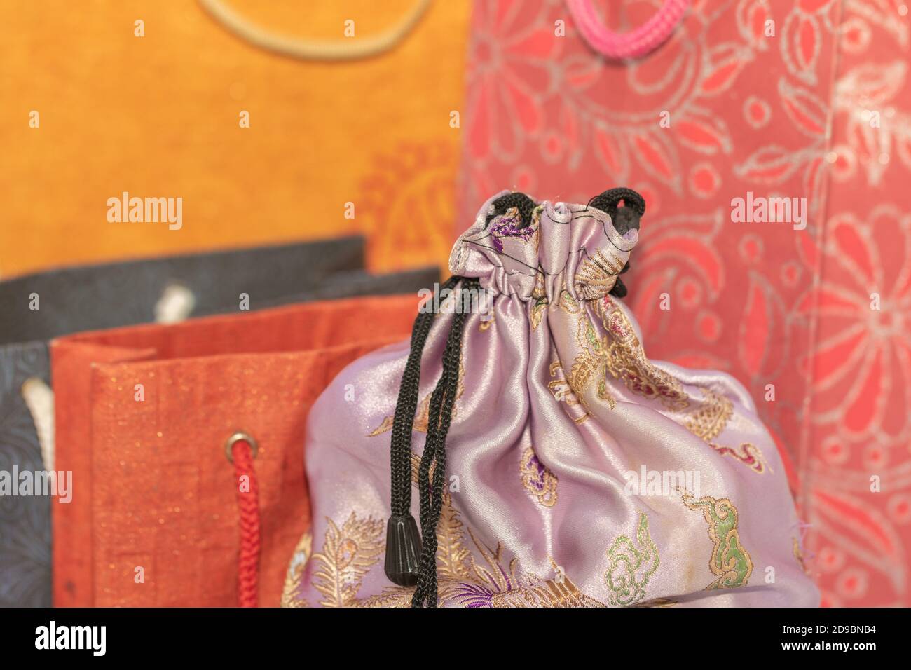 Image de mise au point sélective d'un tissu en soie Housse avec sacs de transport en papier colorés à l'arrière-plan Banque D'Images