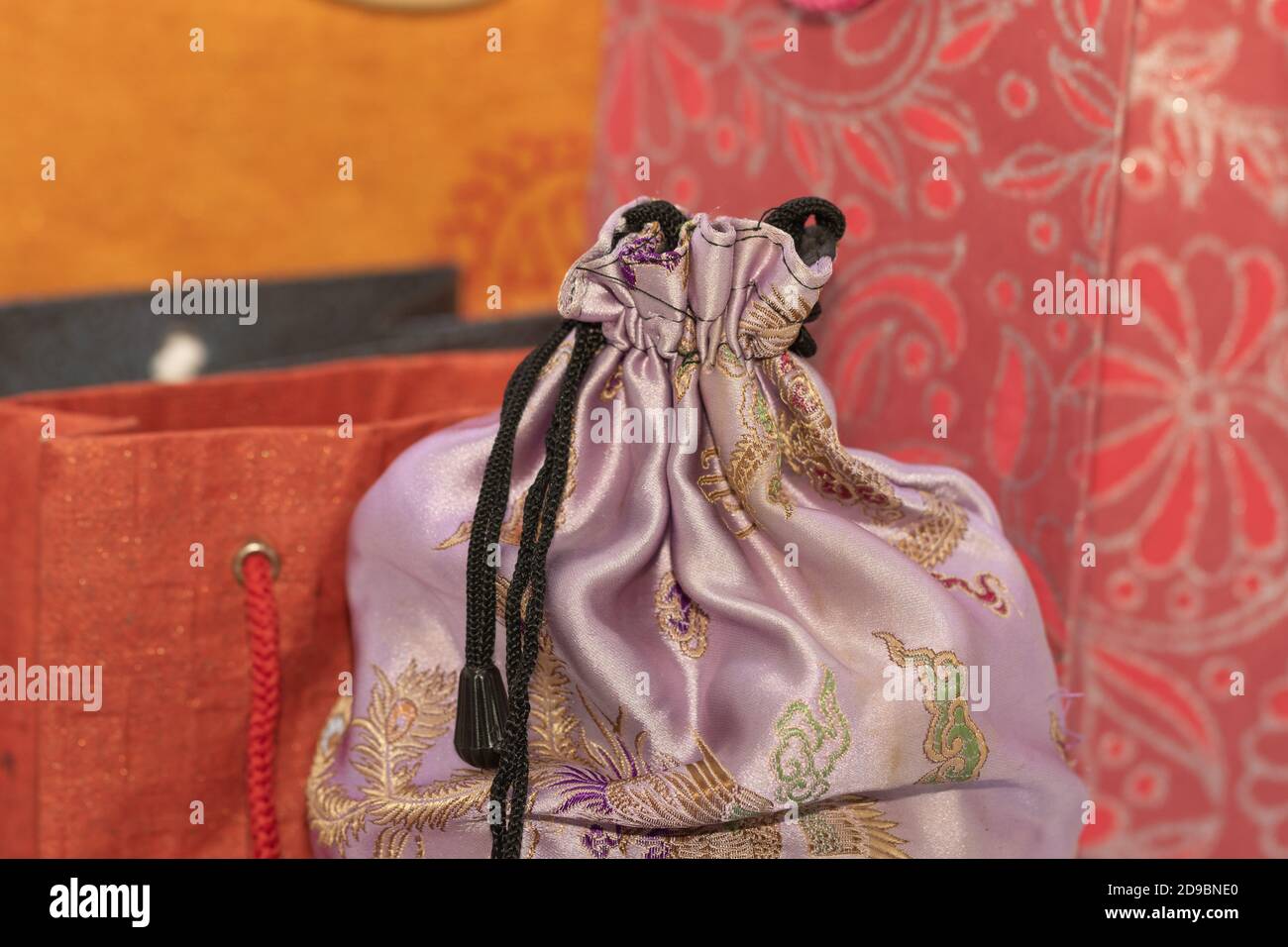 Image de mise au point sélective d'un tissu en soie Housse avec sacs de transport en papier colorés à l'arrière-plan Banque D'Images