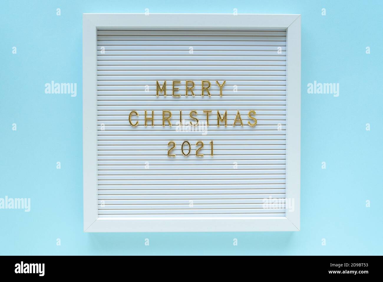 Tableau de lettres avec message d'accueil Joyeux Noël 2021, décorations sur fond bleu pastel. Composition de Noël. Vue de dessus Banque D'Images