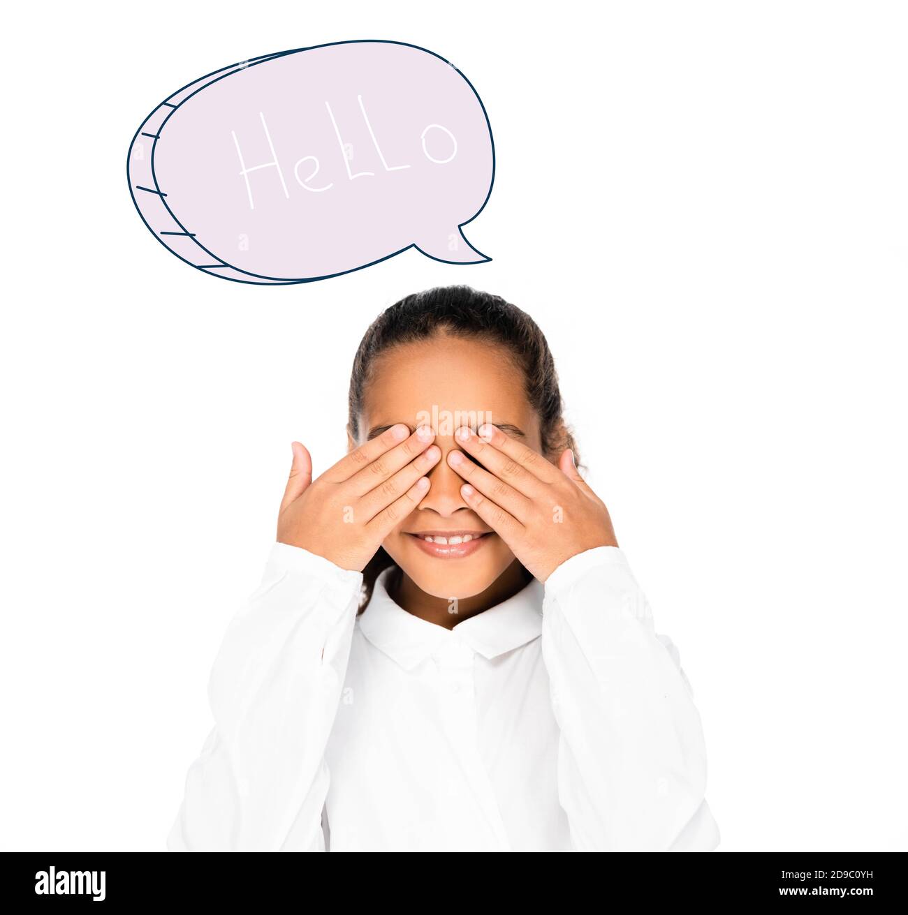 une écolière africaine souriant tout en couvrant les yeux avec des mains isolées sur du blanc, une bulle de discours avec une illustration de la lettre « bonjour » Banque D'Images