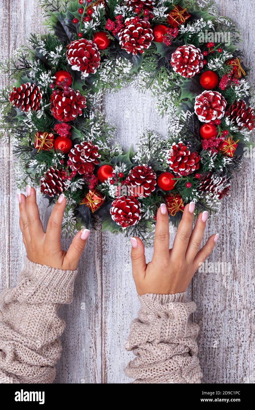 Deux mains dans un chandail beige tricoté avec des plis font une couronne  de Noël artisanale à partir de cônes, branches d'arbre, ornements sur une  table en bois Photo Stock - Alamy