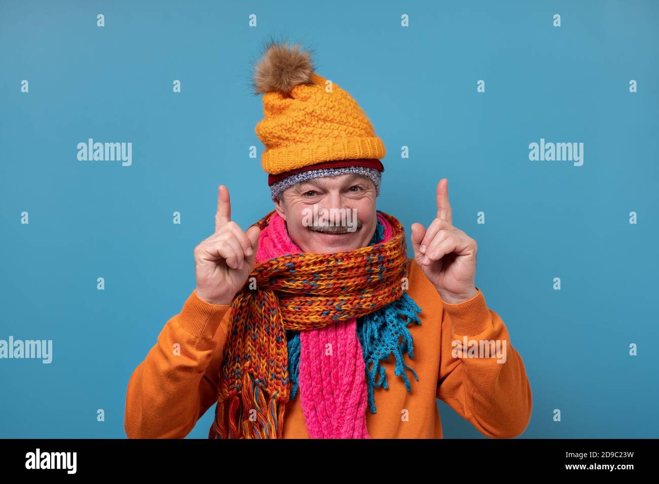 Homme âgé avec moustache portant plusieurs foulards et chapeaux pointant sur le côté Banque D'Images