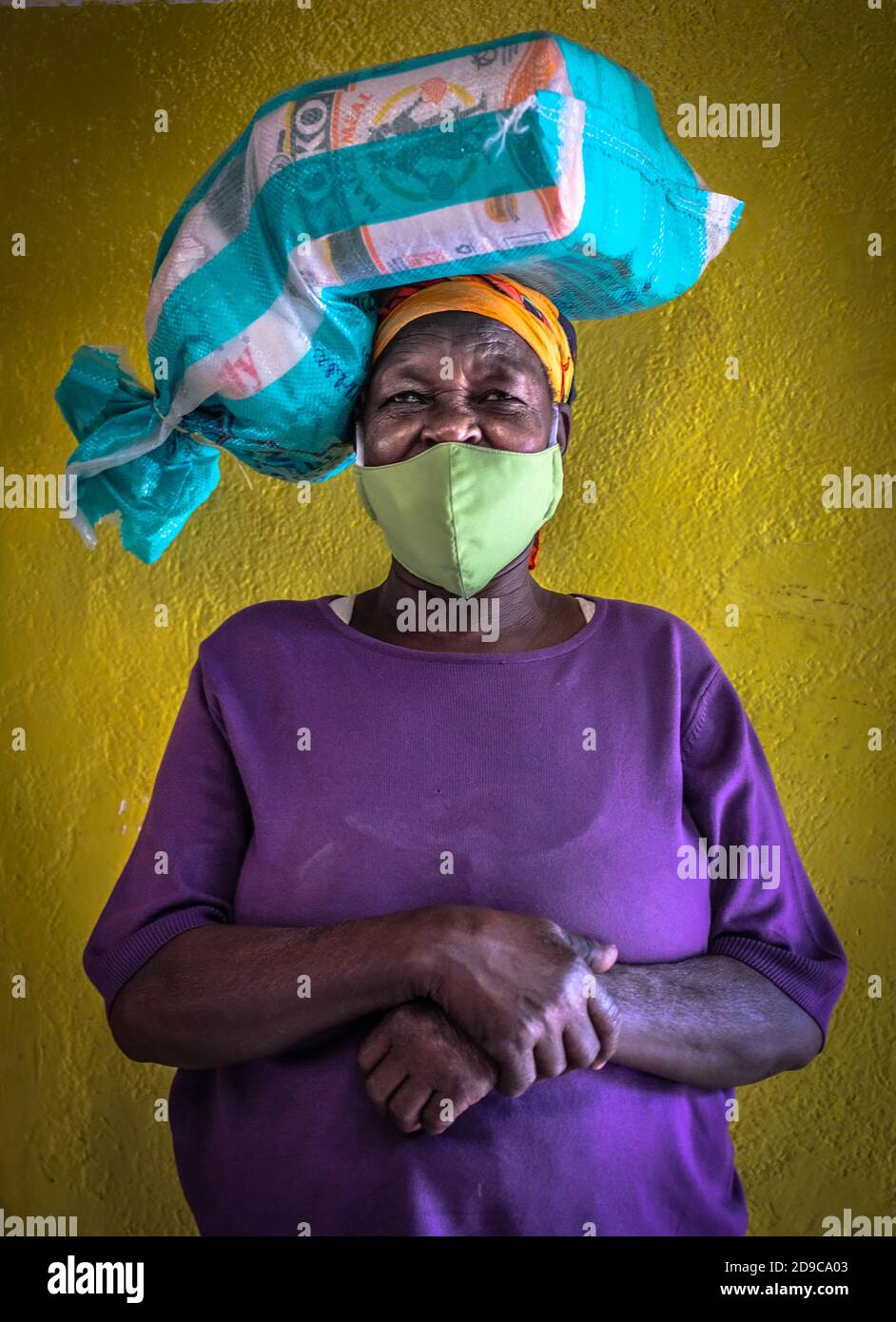 Une femme portant un masque facial revient chez elle après avoir reçu des secours des bons willers pendant la pandémie du coronavirus.le Kenya traverse à nouveau un moment difficile, car le nombre de patients infectés par Covid-19 continue d'augmenter, malgré le fait que beaucoup ne respectent pas les règles et les mesures de sécurité. Banque D'Images