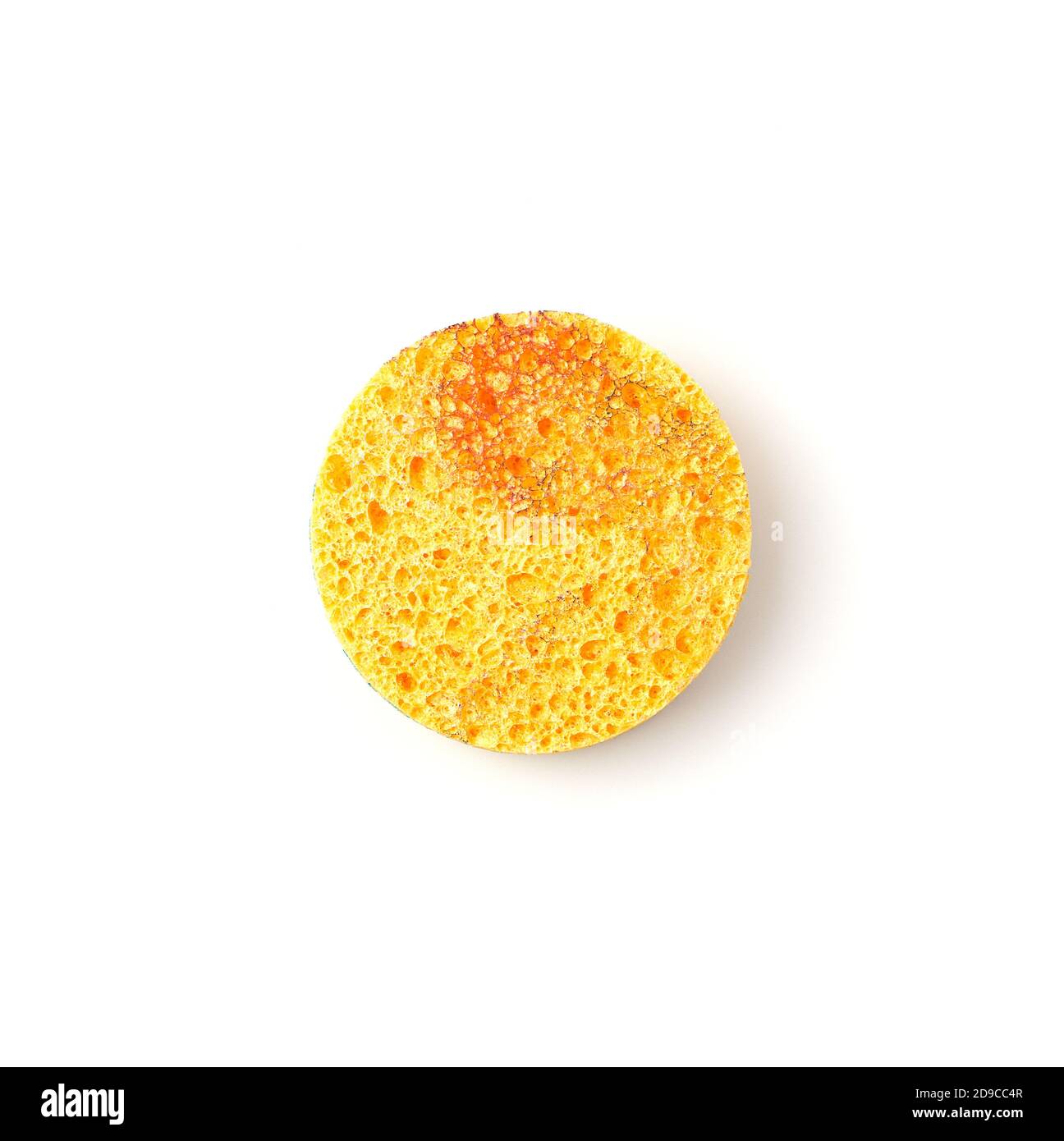 L'éponge jaune ronde pour le nettoyage de la peau est isolée sur un fond blanc. Banque D'Images