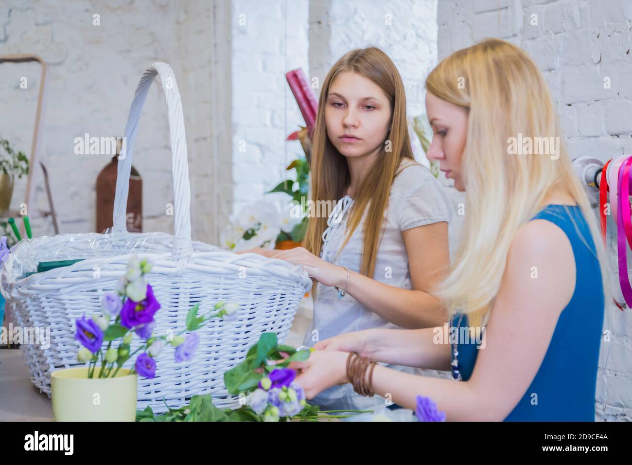 Deux artistes fleuristes professionnels, fleuristes en train de réaliser un grand panier floral avec des fleurs à l'atelier, fleuriste. Fleuriste, fait main, mariage Banque D'Images