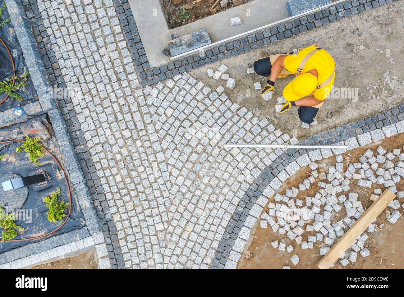 Travailleur de la construction caucasien dans sa 40s Paving Garden Path vue aérienne. Thème de l'architecture du jardin. Banque D'Images