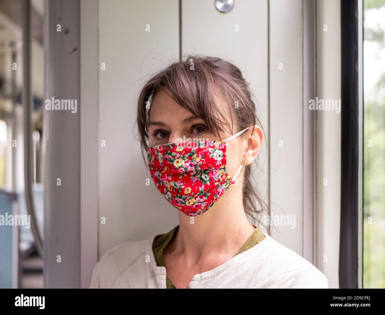 jeune femme portant un masque floral rouge pendant son voyage dans un train Banque D'Images