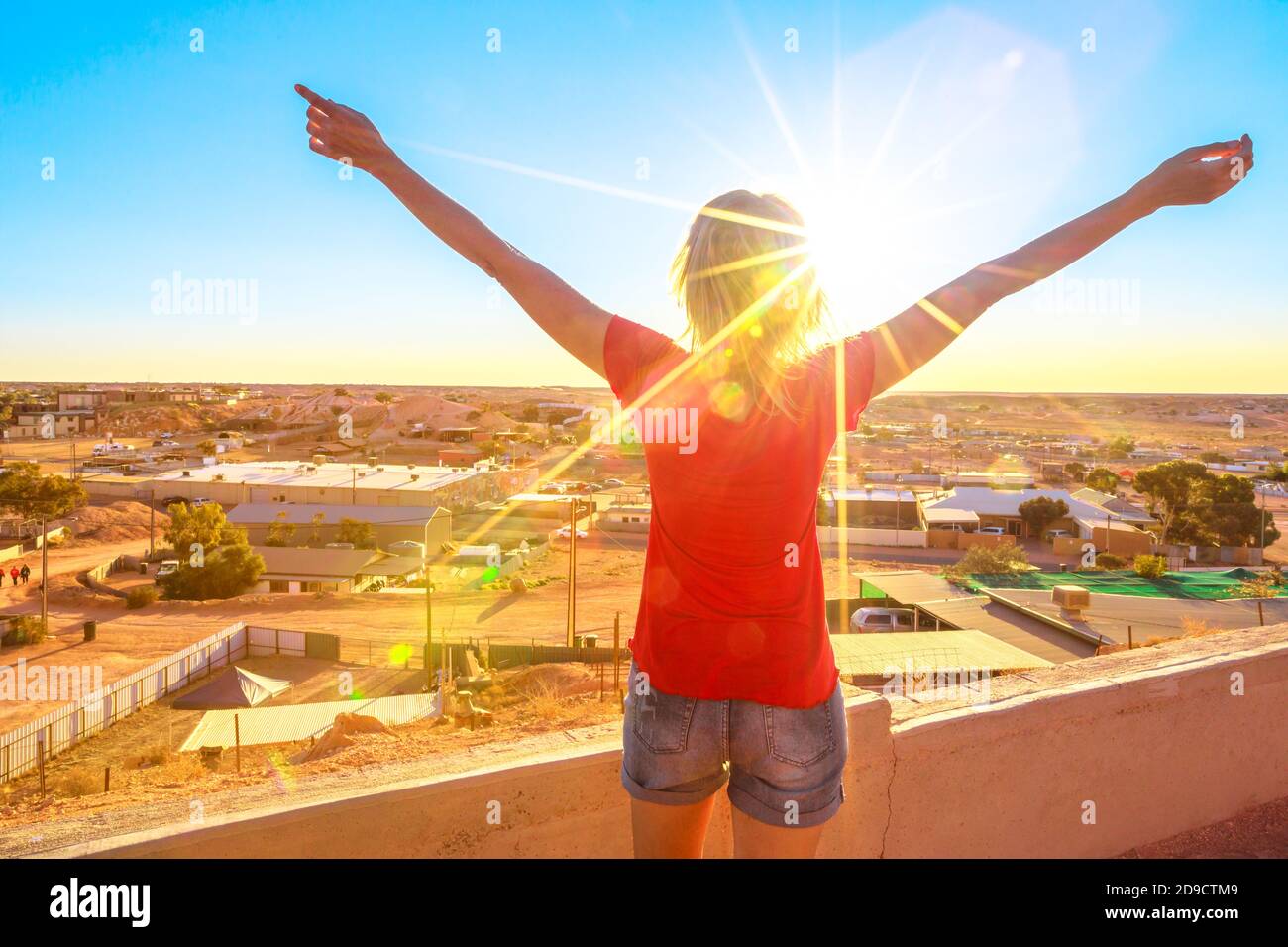 Femme insouciante regardant à bras ouverts la vue panoramique de Coober Pedy au coucher du soleil et le désert environnant depuis le belvédère de la grotte. Outback sud-australien Banque D'Images