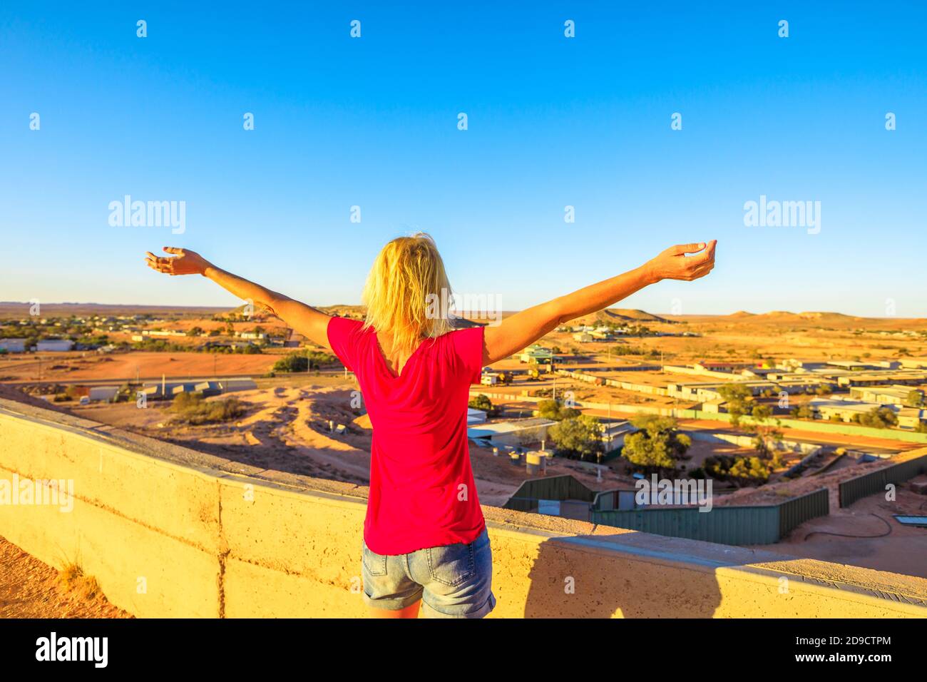 Femme insouciante regardant à bras ouverts la vue panoramique de Coober Pedy au coucher du soleil et le désert environnant depuis le belvédère de la grotte. Outback sud-australien Banque D'Images