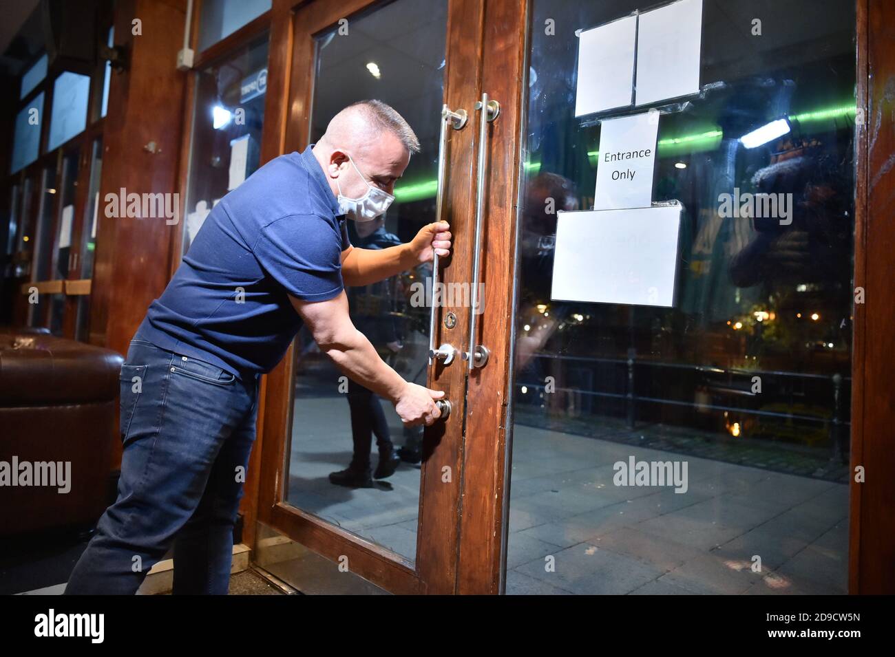 Un travailleur ferme les portes d'un bar du centre-ville de Bristol, devant un confinement national pour l'Angleterre dès jeudi. Banque D'Images