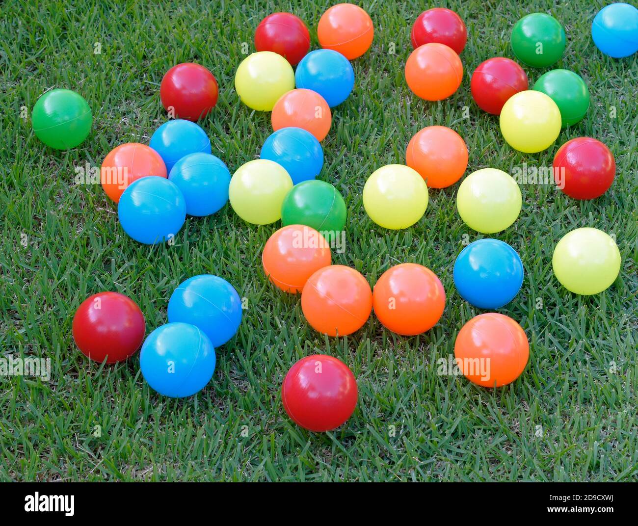 Boules en plastique colorées sur fond d'herbe. Banque D'Images