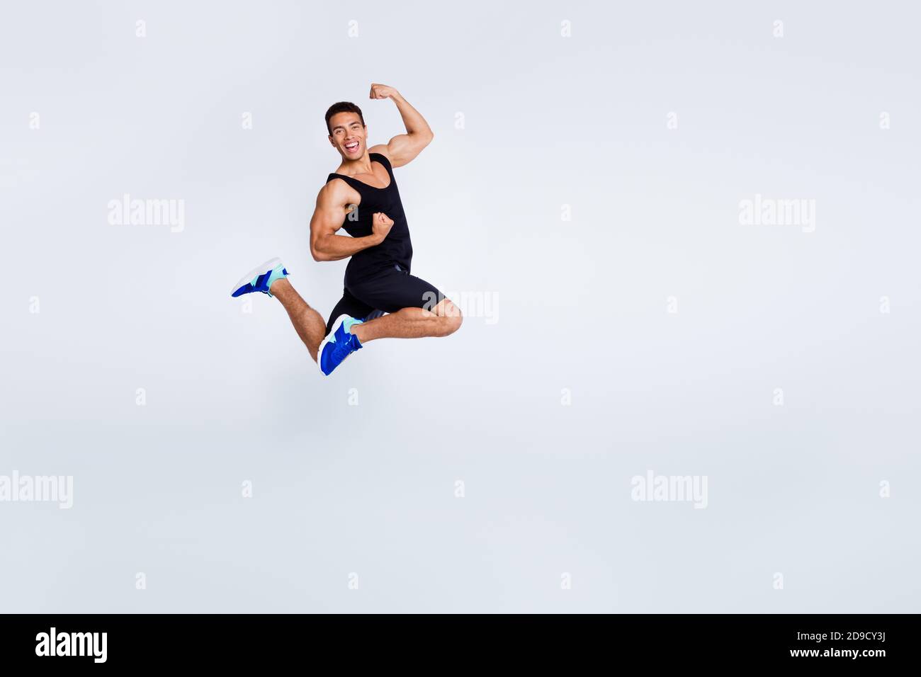Vue sur toute la longueur du corps de son beau attrayant musclé sportive gai gai gai gai gars jumping célébrant se réjouir avoir tasse amusante isolée Banque D'Images