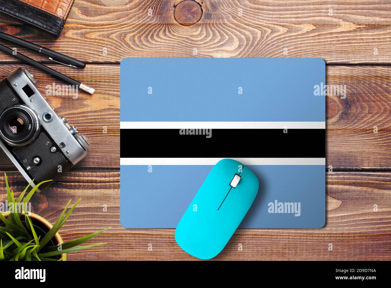 Drapeau du Botswana sur fond en bois avec souris sans fil bleue sur un tapis de souris, vue de dessus. Concept de médias numériques. Banque D'Images