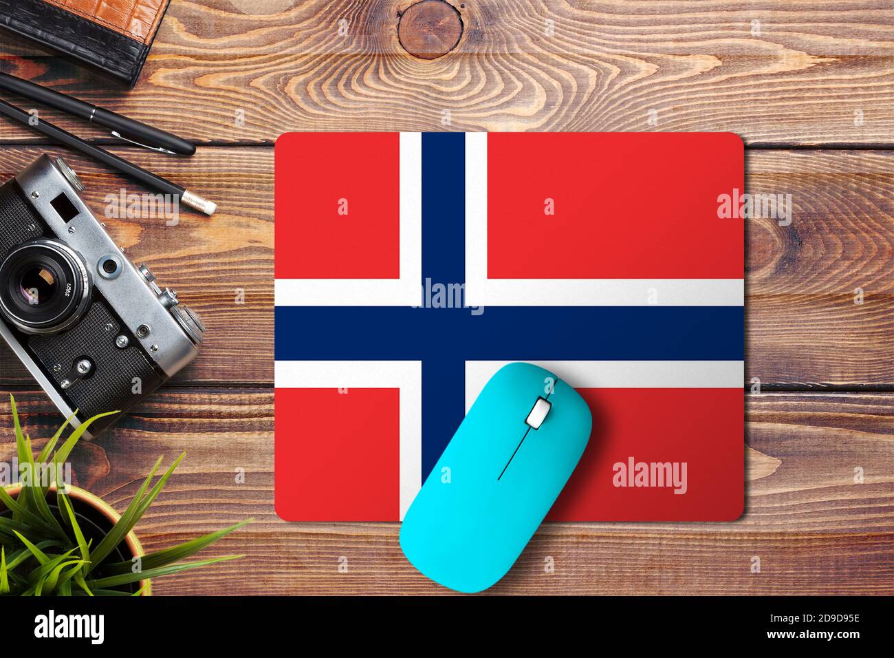 Drapeau norvégien sur fond en bois avec souris sans fil bleue sur tapis de souris, vue de dessus. Concept de médias numériques. Banque D'Images