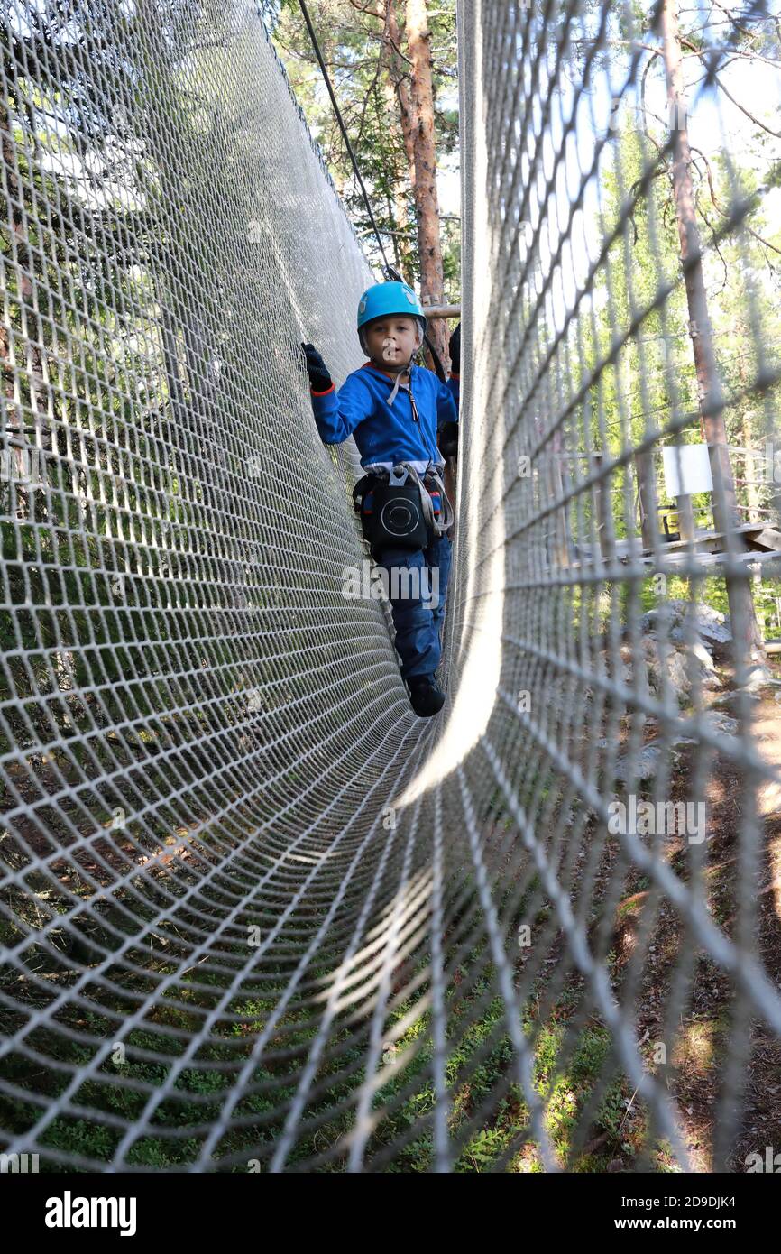 Enfant surmontant un obstacle en mesh dans un parc à cordes, Karelia Banque D'Images