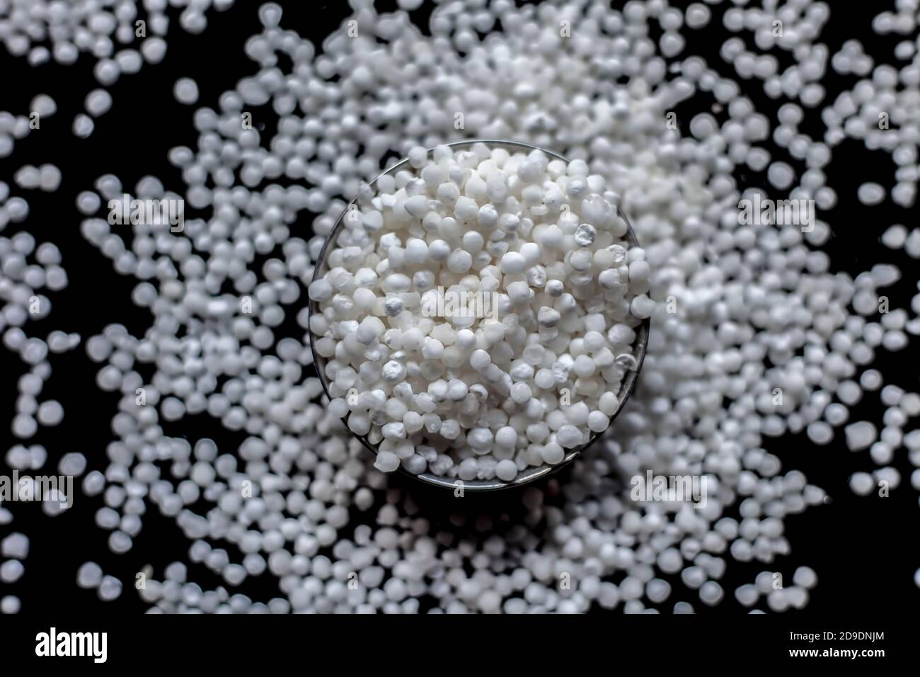 Gros plan de perles de sagou brutes ou de perles de tapioca dans une plaque de verre sur une surface noire. Banque D'Images