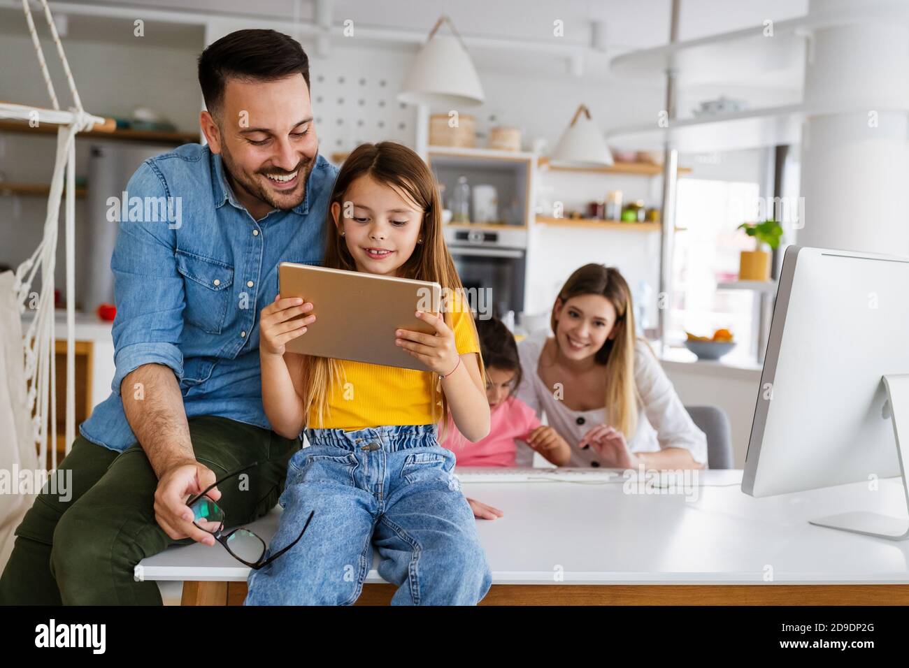 Une famille heureuse qui passe du temps à la maison et utilise des appareils numériques. Banque D'Images