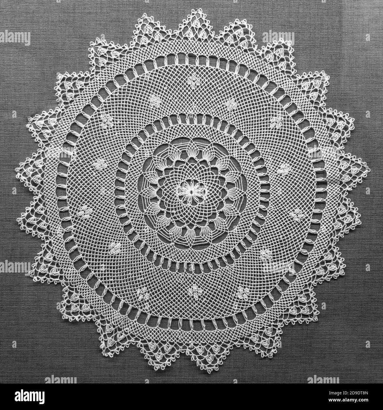 Dentelle faite à la main sur fond noir. Dentelle en tissu Macrame doily. Serviette décorative en dentelle blanche crochetée Banque D'Images