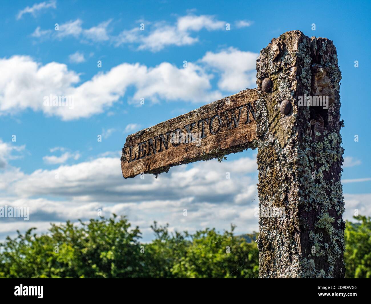Un vieux panneau en bois recouvert de lichens pointant vers le Direction Lennoxtown Banque D'Images