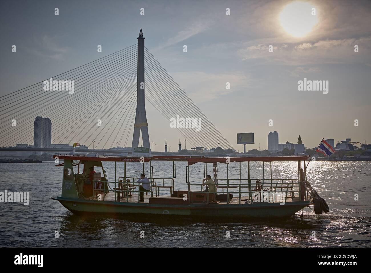 Bangkok, Thaïlande, mars 2016. Un ferry pour les transports en commun à côté d'un pont suspendu sur la rivière Chao Phraya. Banque D'Images