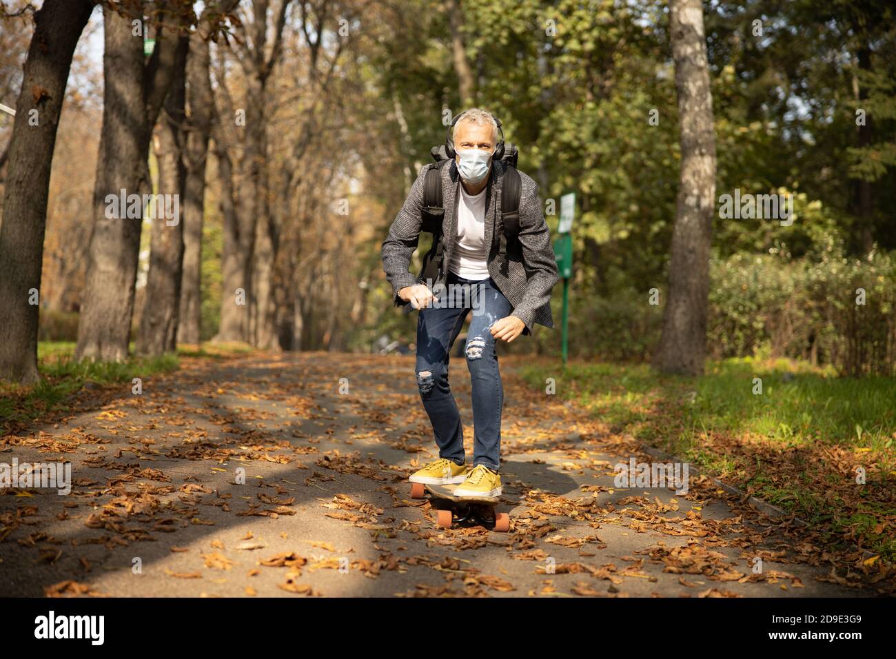 Joyeux homme mûr roulant de planche à roulettes dans le parc Banque D'Images