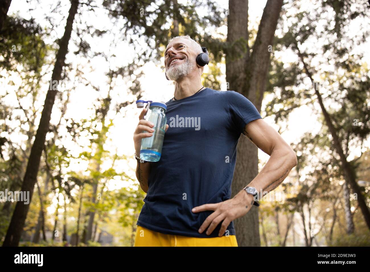 Joyeux homme athlétique qui fait du jogging en forêt Banque D'Images