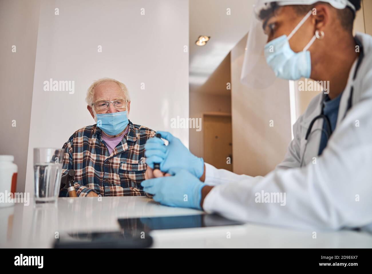 Médecin gériatrique prenant un échantillon de sang capillaire du patient Banque D'Images