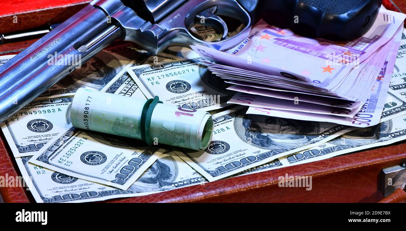 Valise de concept de vol plein de dollars volés Revolver Smith e Wesson 357 manum sur un fond de dollars de 100 dollars de billets de banque Banque D'Images