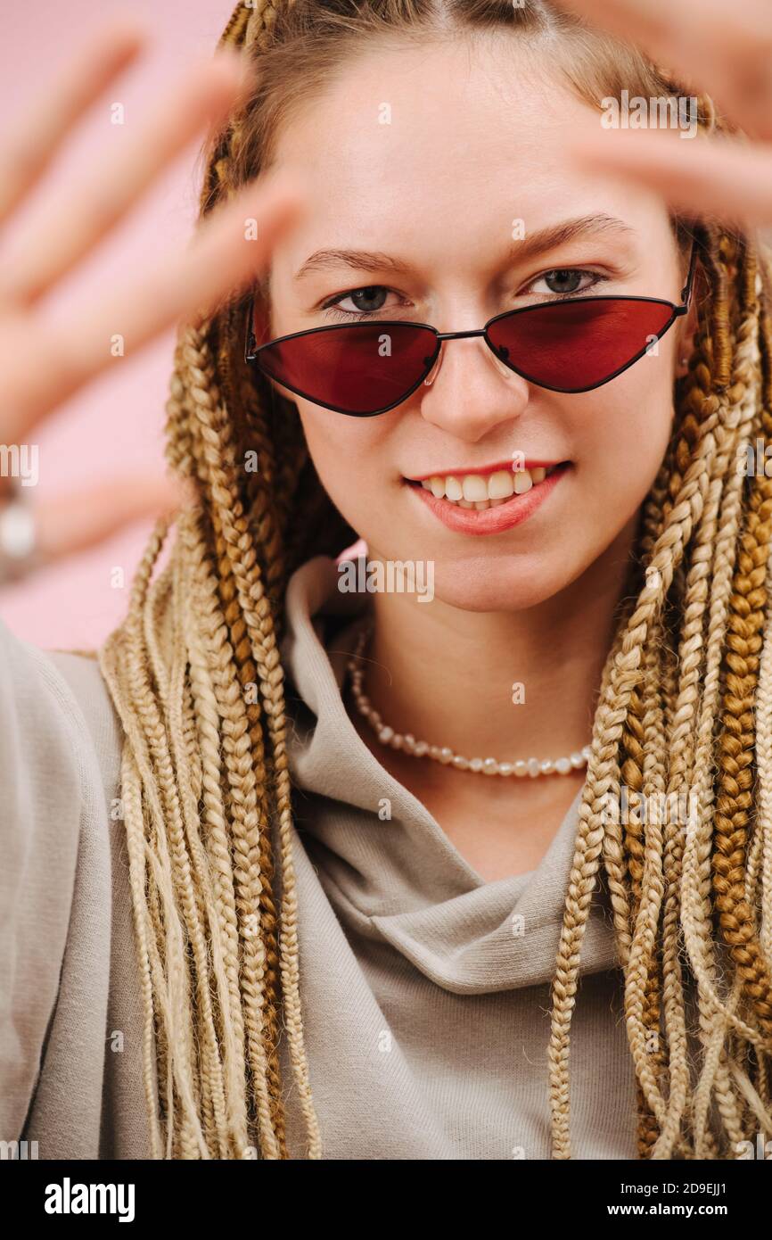 Femme excentrique dans des lunettes de soleil avec blonde élégant braids afro plus rose Banque D'Images