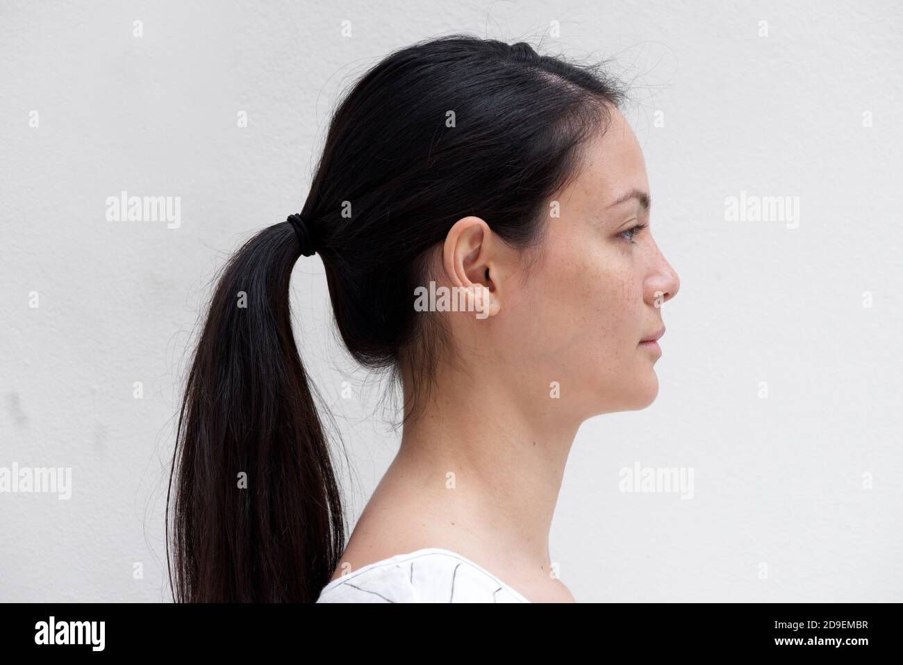 Gros plan portrait de profil jeune femme asiatique avec une expression sérieuse sur fond blanc Banque D'Images