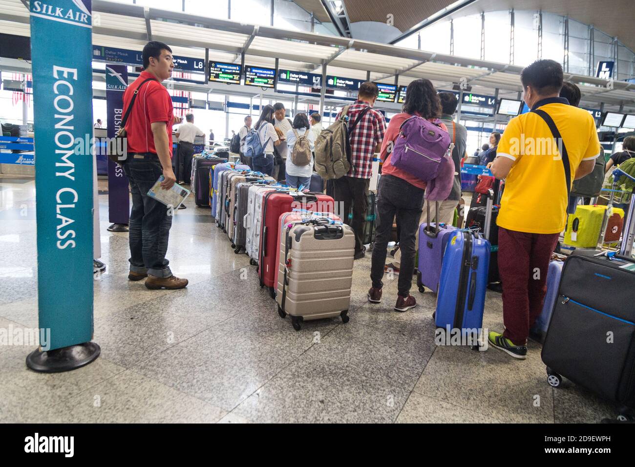 Passager avec file d'attente de bagages au comptoir d'enregistrement de KLIA Aéroport Banque D'Images