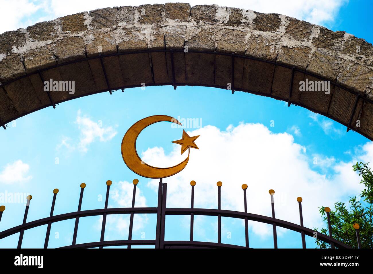 Crescent lune et étoile sur un fond bleu ciel nuageux. Arche de pierre. Partie de la grille métallique. Banque D'Images