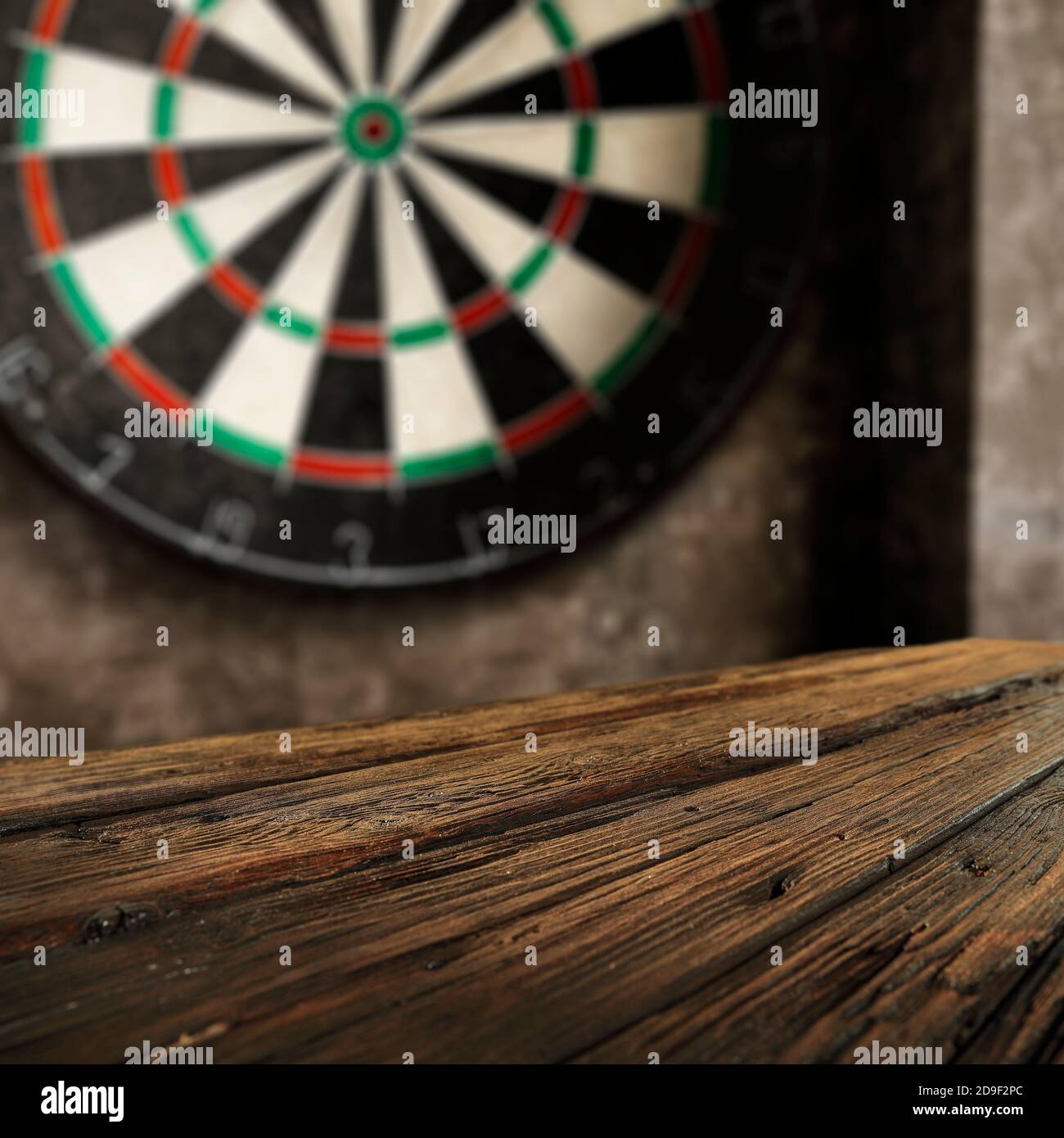 Fond de table en bois vide et espace de copie pour la nourriture et les boissons et les produits avec jeu de fléchettes sur le mur gris. Banque D'Images