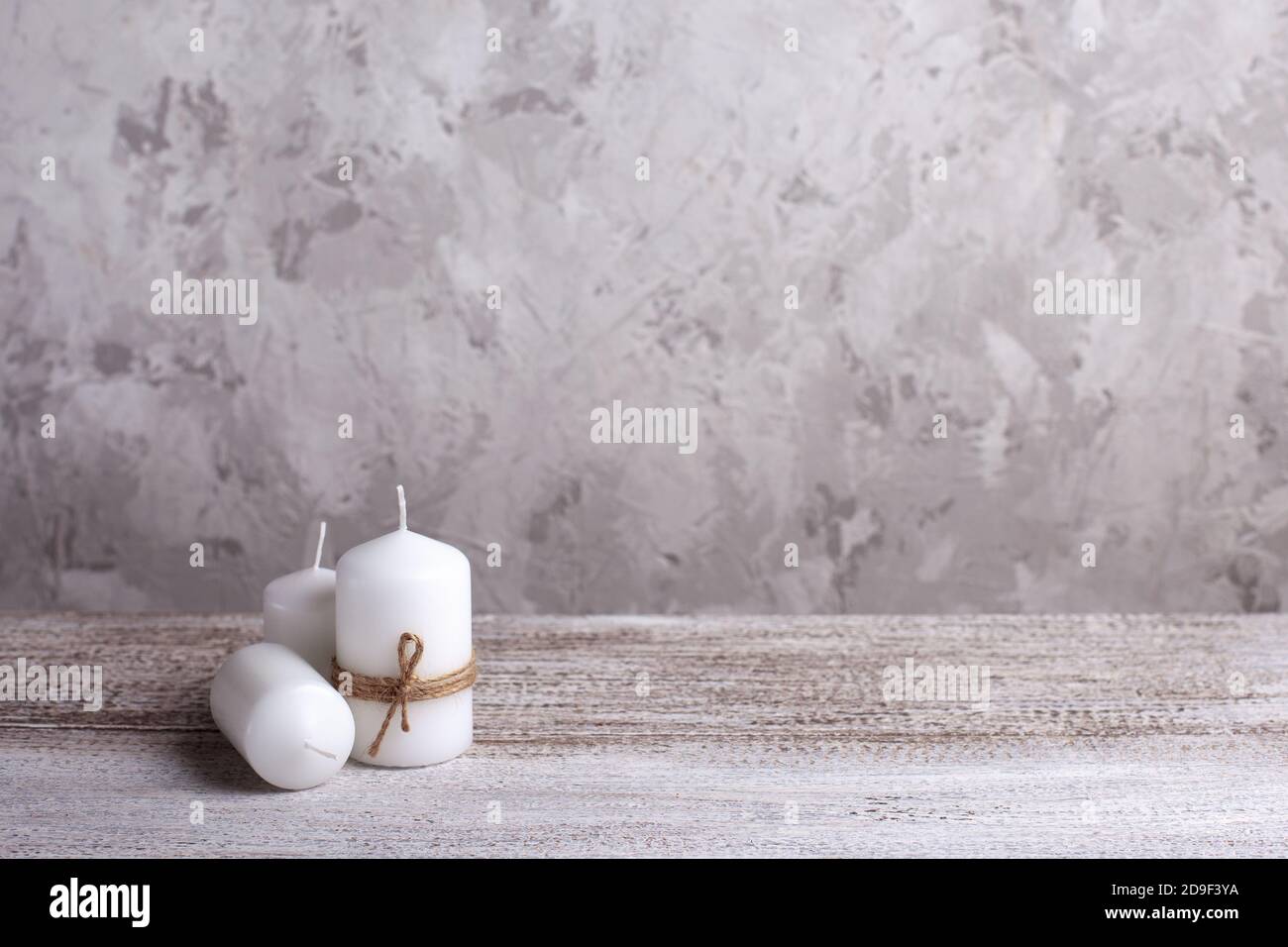 maquette de trois bougies blanches dans une corde de jute sur une table en bois, une bougie couchée sur son côté Banque D'Images