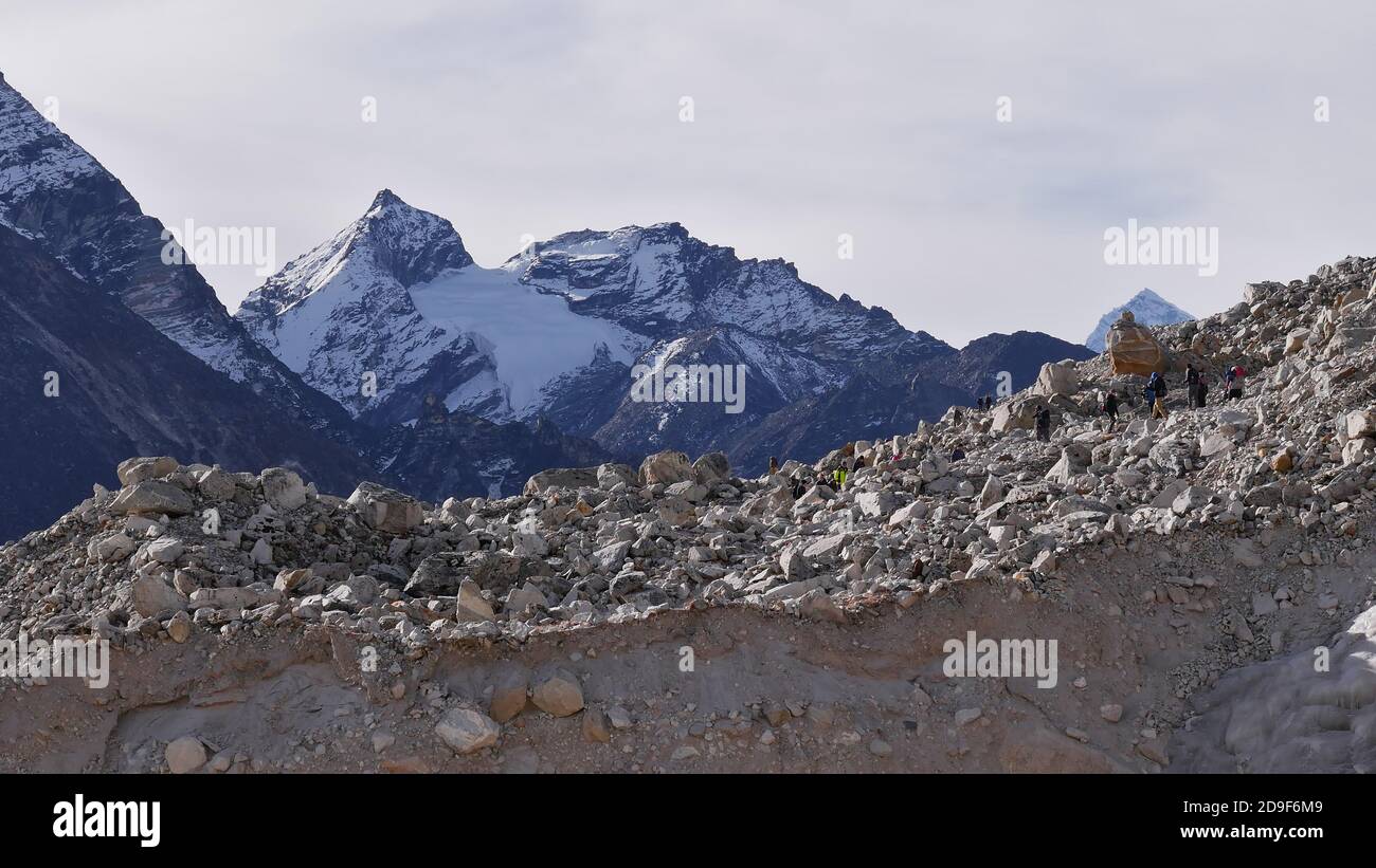 Groupe de randonneurs grimpant à travers le majestueux glacier Khumbu couvert de rochers sur la route du village Gorakshep sur l'Everest base Camp Trek, Népal. Banque D'Images