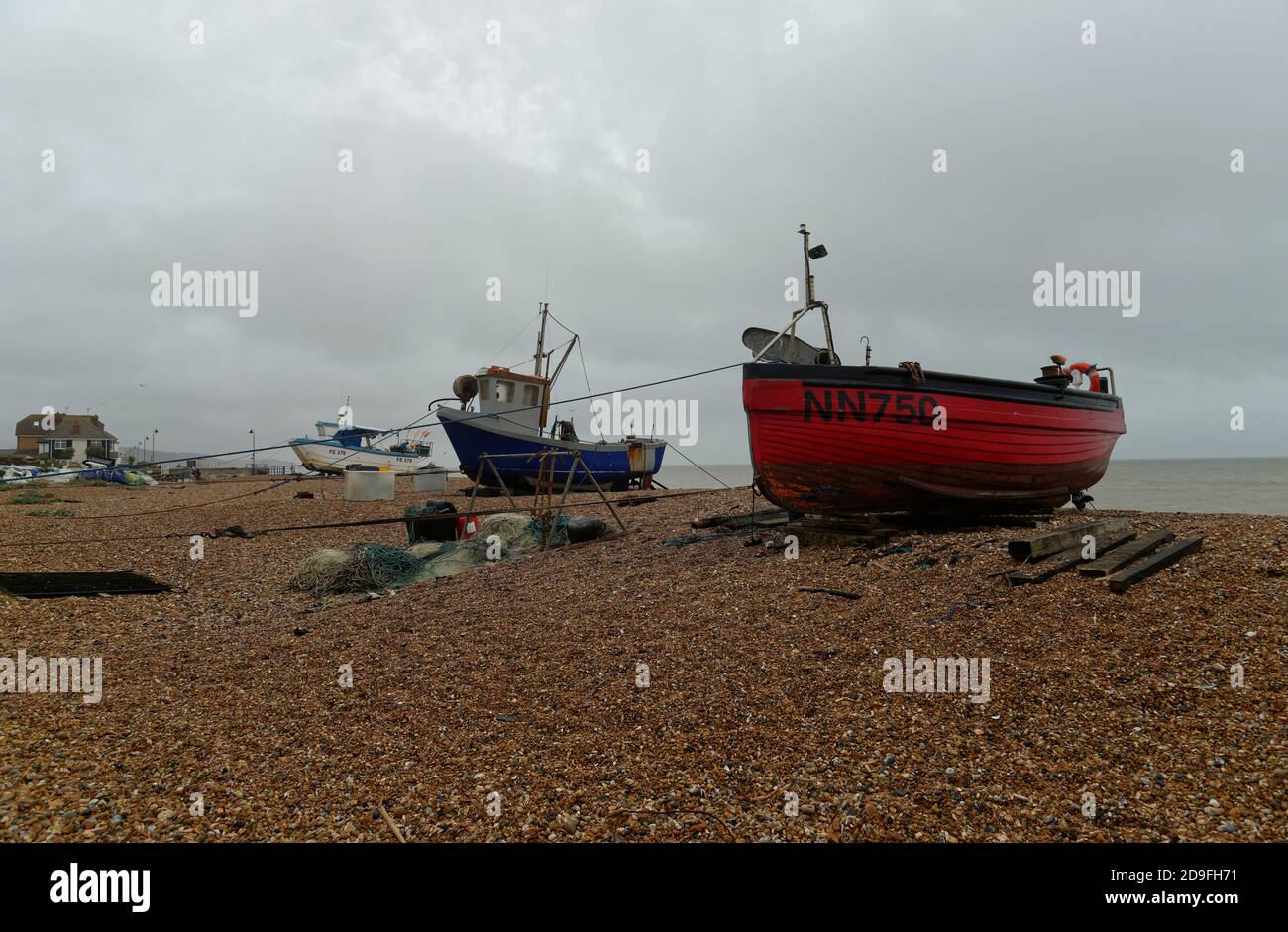 Bateau de pêche rouge sur une plage près de Hythe dans le Kent, Angleterre, Royaume-Uni. Banque D'Images