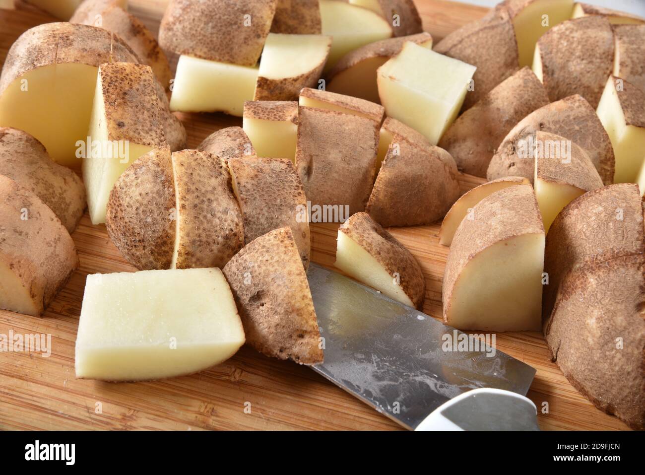 Coupez les pommes de terre en dés sur une planche à découper Banque D'Images