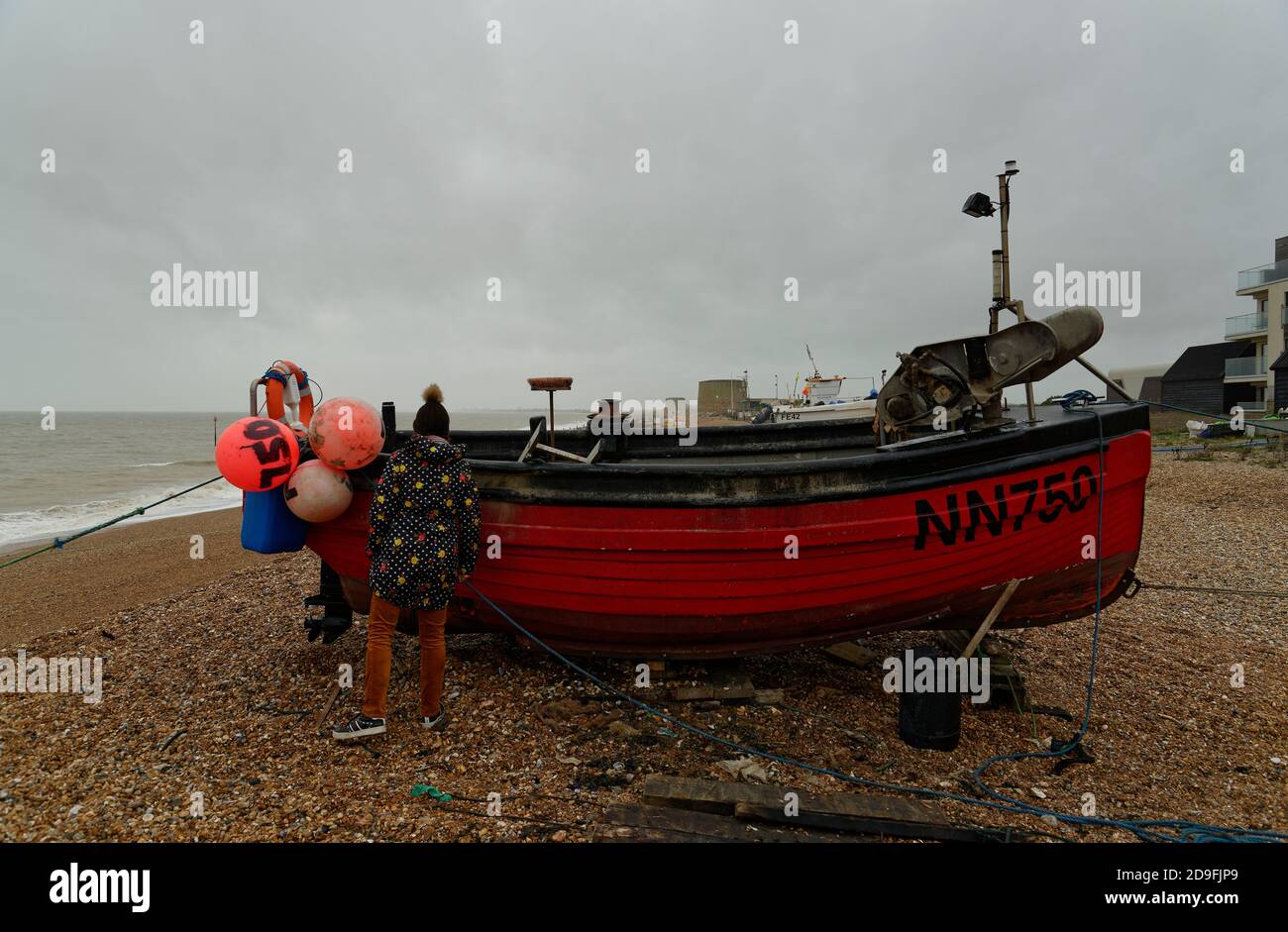 Bateau de pêche rouge sur une plage près de Hythe dans le Kent, Angleterre, Royaume-Uni. Banque D'Images