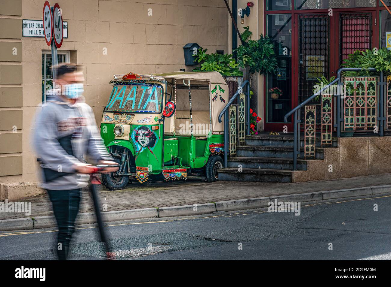 La vie quotidienne. Jeune homme sur un scooter portant un masque facial traversant la route. La jeunesse contre le vieux concept. Banque D'Images