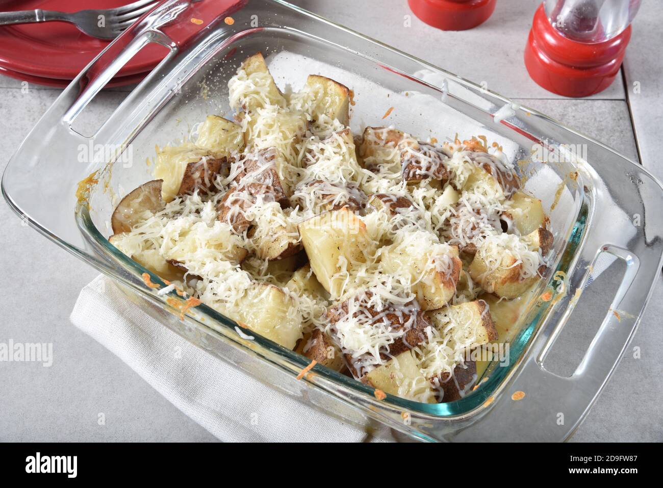 Fromage râpé fondant sur des cubes de pommes de terre cuits dans un plat de cocotte. Banque D'Images