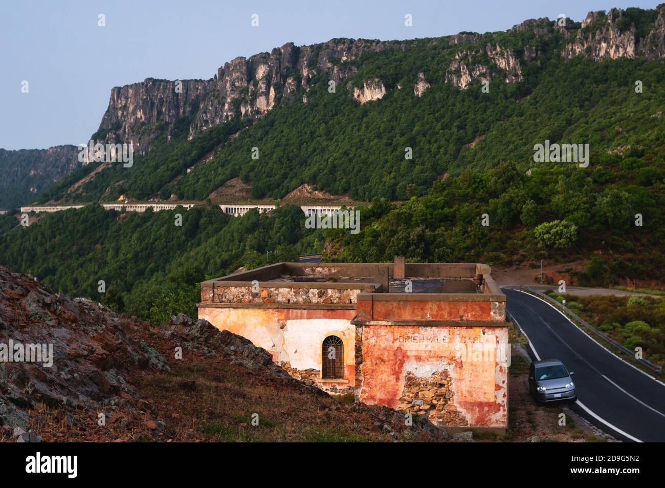 Maison de travailleur routier sur une route de montagne en Sardaigne, Italie. Petite voiture parkes sur le côté. Jour de pluie dans la soirée Banque D'Images