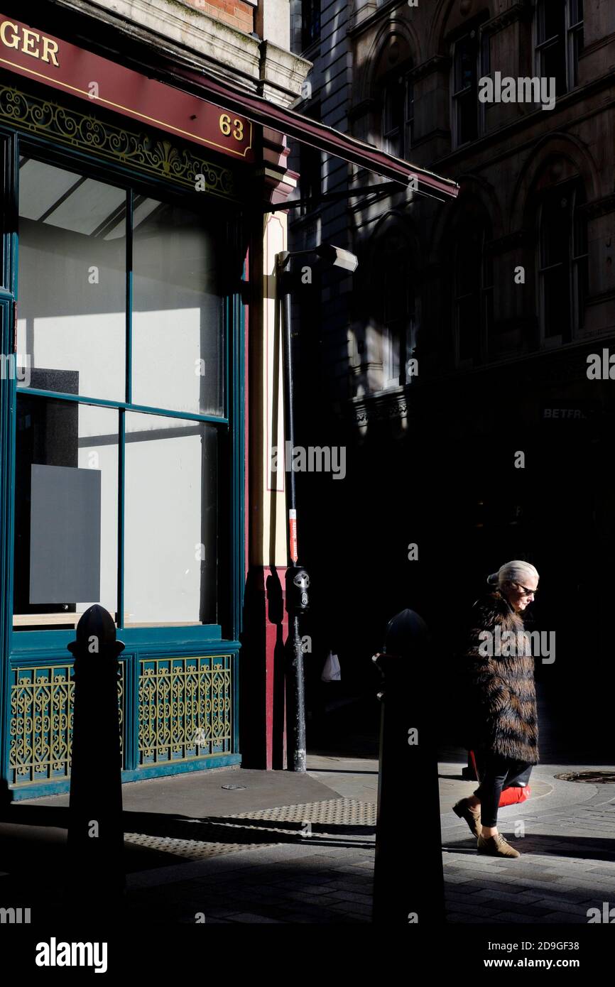 Photographie de rue à Londres : une femme marche en plein soleil d'hiver dans la ville de Londres. Banque D'Images