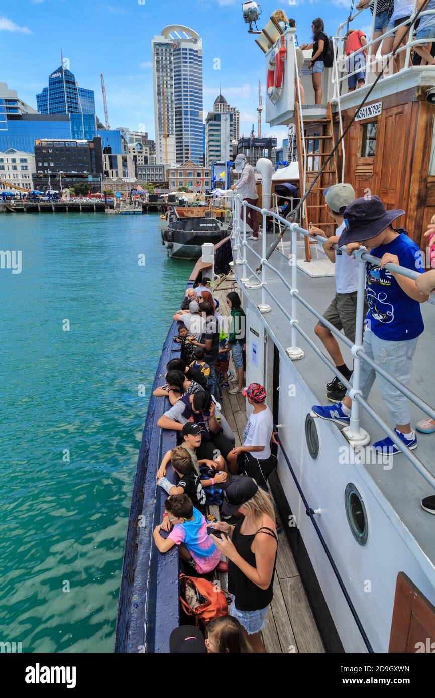 Passagers bordant les chemins de fer du William C Daldy, un remorqueur historique, lorsqu'il retourne à Auckland, Nouvelle-Zélande, après une croisière dans le port Banque D'Images