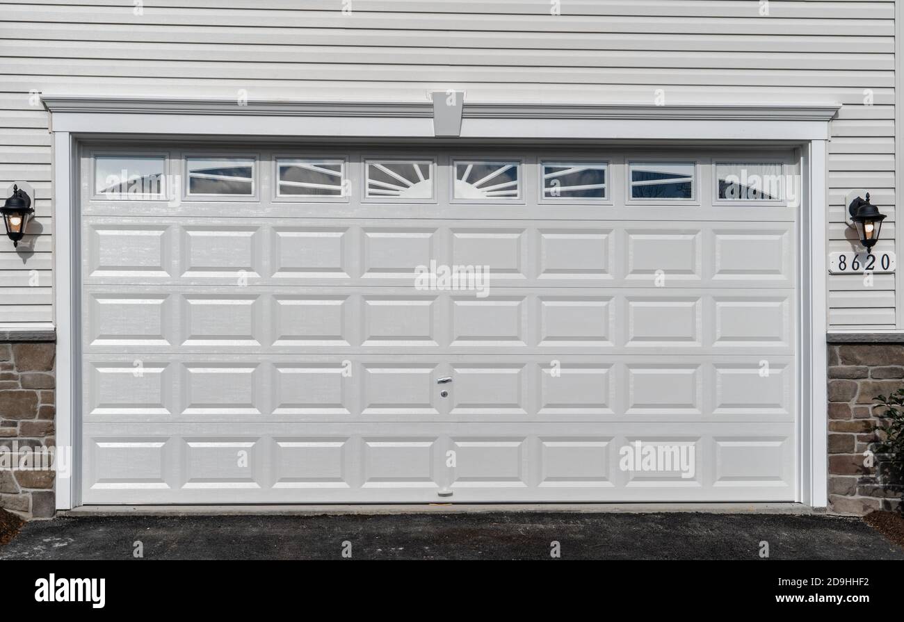 Double voiture classique isolée en acier à panneaux surélevés porte de garage encadrée avec une garniture blanche pour ajouter de l'accent, sur une nouvelle maison américaine Banque D'Images