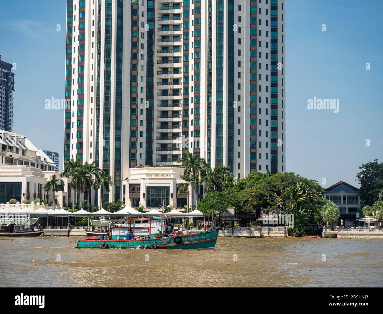 L'Hôtel Peninsula sur la rive de la rivière Chayo Phraya à Bangkok, avec un remorqueur en premier plan. Banque D'Images
